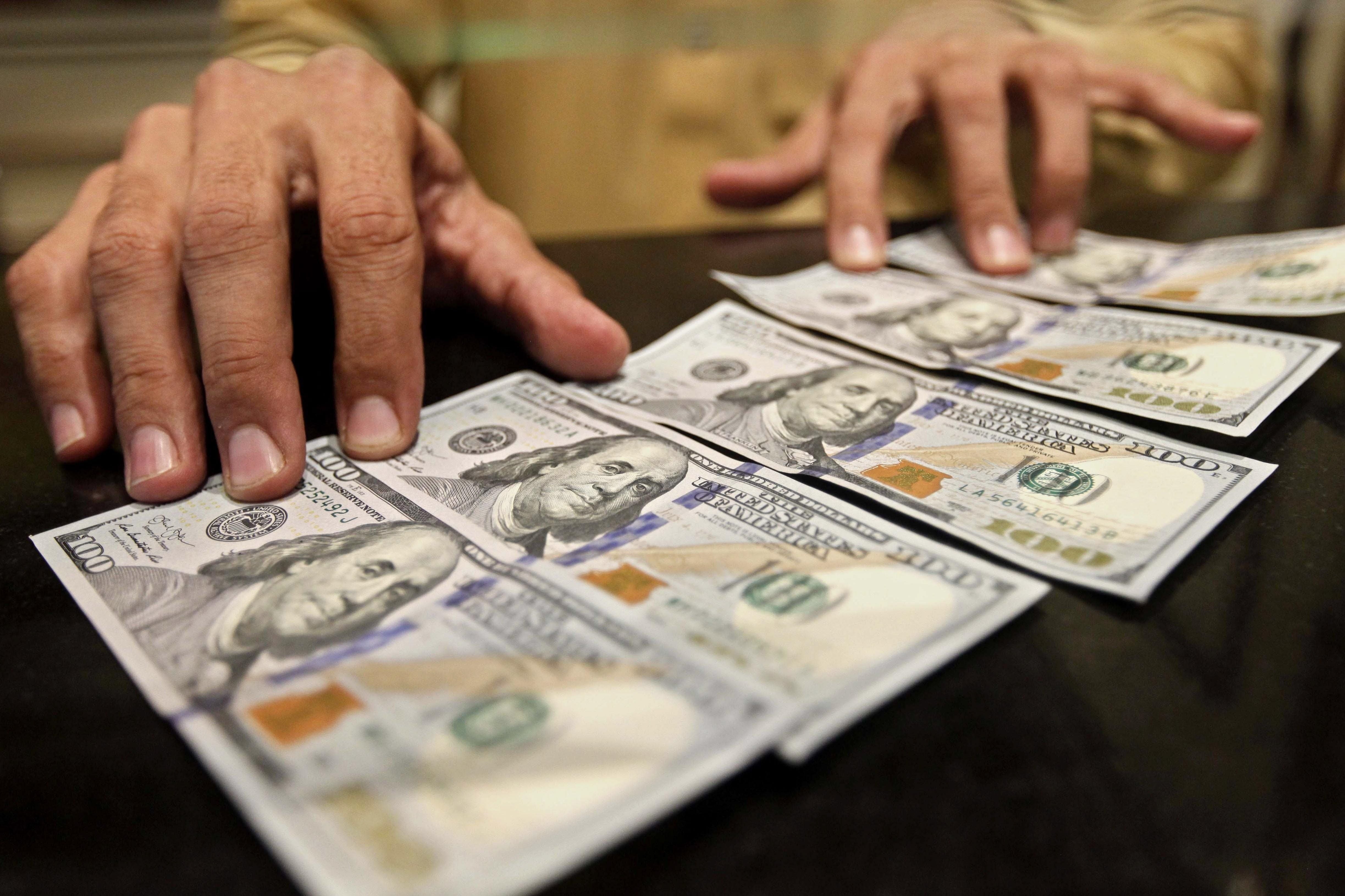 Un hombre sostiene unos billetes de dólar estadounidense (Foto: AFP)