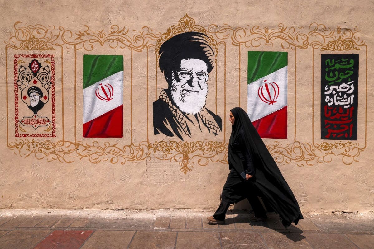 Una mujer pasa junto a un mural que representa al difunto líder supremo de Irán, Ali Khamenei, en la plaza Valiasr, en el centro de Teherán, el 8 de agosto de 2026. Foto: ATTA KENARE / AFP