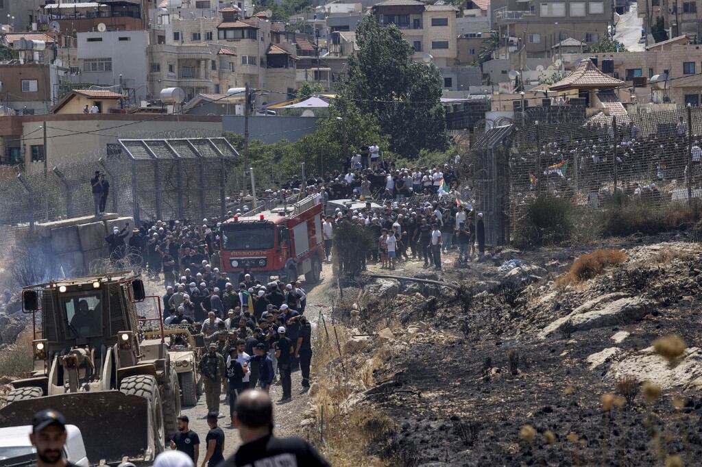 Miembros de la comunidad drusa de ambos lados cruzan la zona de amortiguación entre Siria y los Altos del Golán, anexionados por Israel, cerca de Majdal Shams, el 16 de julio de 2025. El 16 de julio, las tropas israelíes intentaron controlar a las multitudes e impedir que los drusos cruzaran la frontera con Siria, tras la violencia mortal en el sur del país que obligó a Damasco a desplegar fuerzas gubernamentales. (Foto de Jalaa MAREY / AFP)