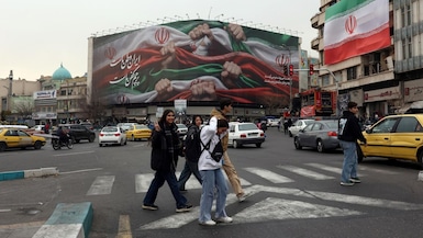 Jóvenes iraníes caminan junto a una valla publicitaria con el lema «Irán es nuestra patria» en la plaza Enqelab de Teherán, Irán, el 13 de enero de 2026. Foto: EFE/EPA/ABEDIN TAHERKENAREH