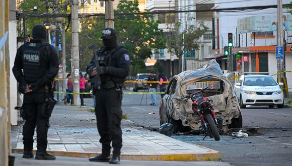 Dos policías hacen guardia junto a los restos de un automóvil después de que explotó en Quito el 31 de agosto de 2023. Un coche bomba explotó en una zona comercial de la capital de Ecuador sin causar víctimas, dijo la policía, mientras el país experimenta un aumento de la violencia relacionada con el tráfico de drogas. (Foto de Rodrigo BUENDÍA / AFP)