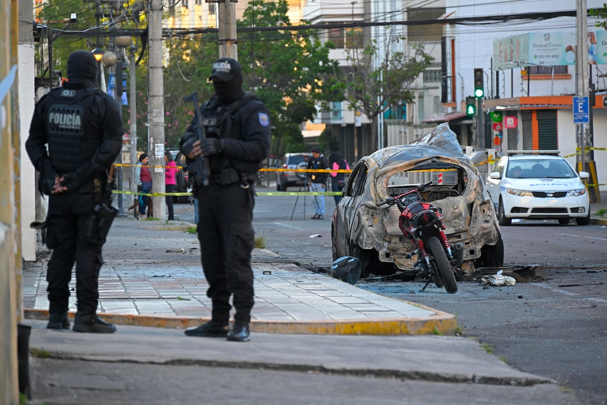 Dos policías hacen guardia junto a los restos de un automóvil después de que explotó en Quito el 31 de agosto de 2023. Un coche bomba explotó en una zona comercial de la capital de Ecuador sin causar víctimas, dijo la policía, mientras el país experimenta un aumento de la violencia relacionada con el tráfico de drogas. (Foto de Rodrigo BUENDÍA / AFP)