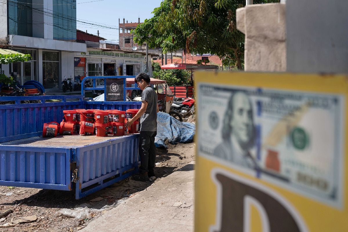 Un trabajador descarga cubos de grasa para maquinaria cerca de una oficina de cambio situada en el centro de Puerto Maldonado.
