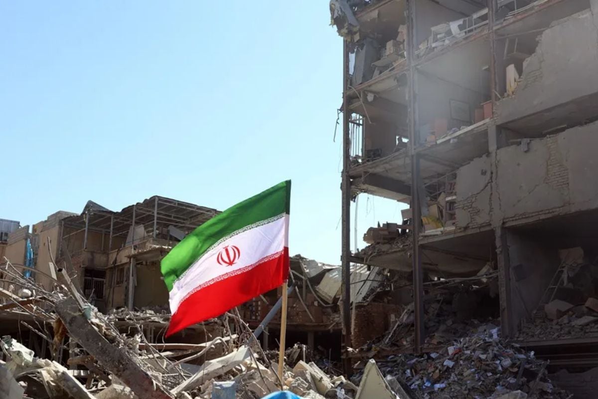 Una bandera de Irán ondea ante un edificio dañado en ataque aéreo contra en el centro de Teherán. Foto: EFE/EPA/Abedin Taherkenareh