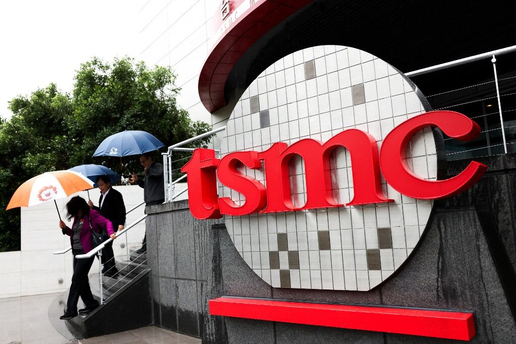 (ARCHIVO) Gente camina junto al logotipo de Taiwan Semiconductor Manufacturing Company (TSMC) en el exterior del Museo de Innovación de la empresa en su sede en Hsinchu el 21 de noviembre de 2024. (Foto de I-Hwa CHENG / AFP)