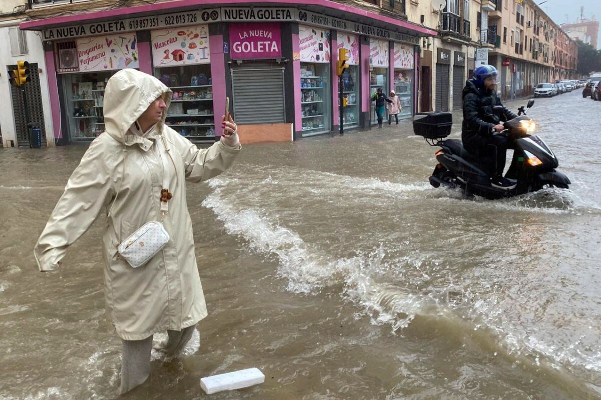 Una mujer hace fotos con el agua hasta las rodillas en Málaga donde las fuertes trombas de agua y granizo que se registran este miércoles 13 de noviembre han causado inundaciones y la acumulación de grandes balsas en algunas de las principales avenidas de todos los distritos de la ciudad. (Foto: EFE)