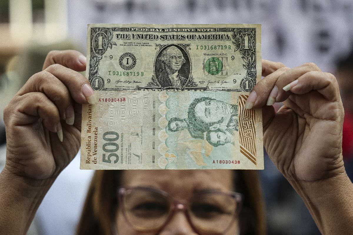 Una mujer sostiene un billete de 1 dólar estadounidense y uno de 500 bolívares durante una protesta por mejores salarios en Caracas, el 26 de febrero. Fotógrafo: Jesus Vargas/Getty Images