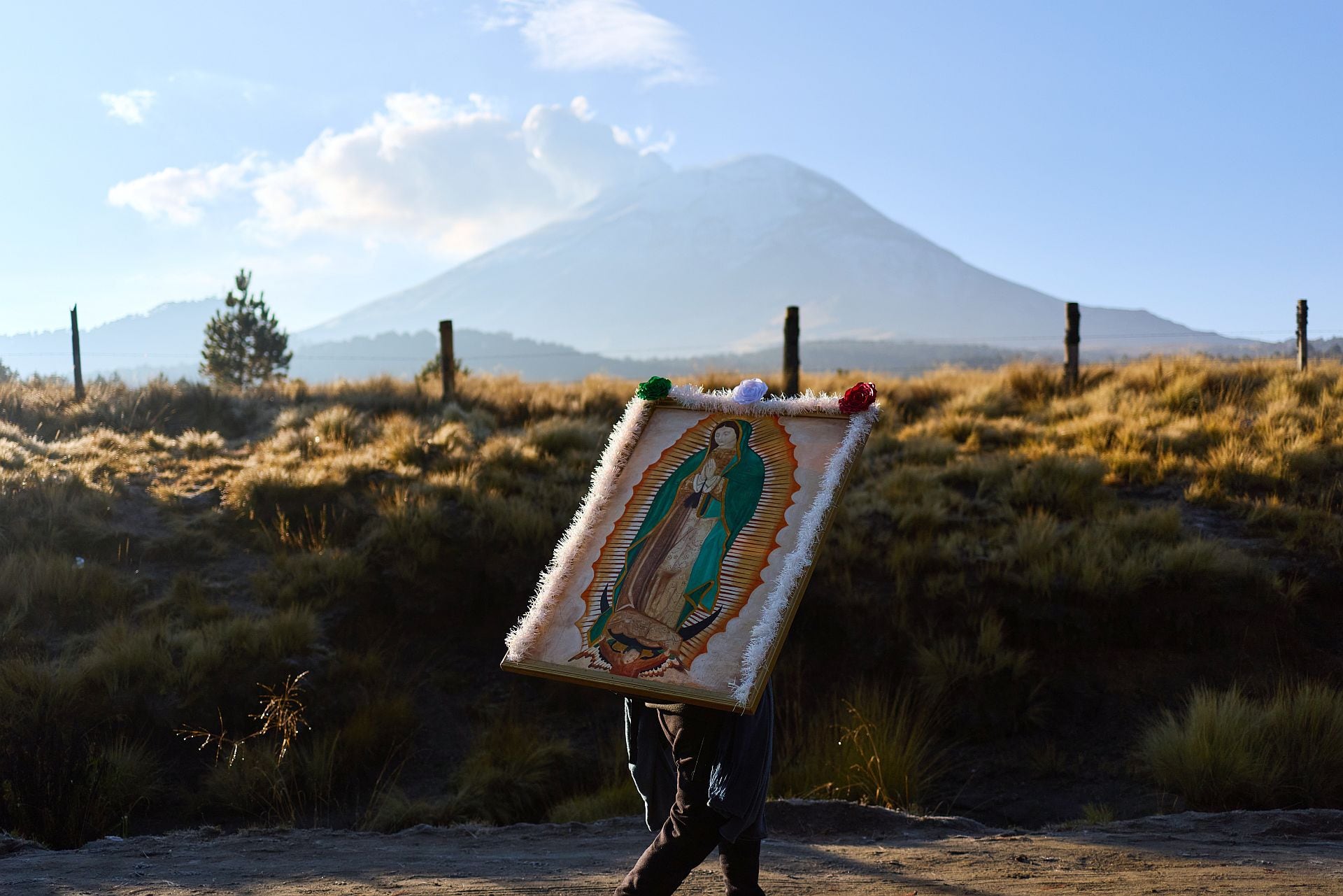 Un peregrino, que carga con una imagen de la Virgen de Guadalupe, pasa caminando por delante del Popocatepetl, en Paso de Cortés, de camino a la Ciudad de México, el 10 de diciembre de 2025. (AP Foto/Claudia Rosel)