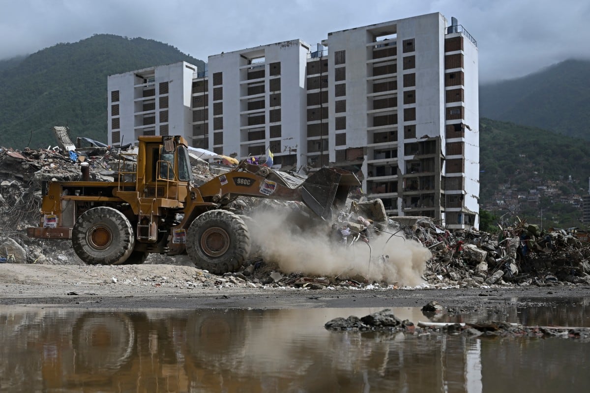 Una minicargadora trabaja frente a los restos derrumbados de un edificio residencial que colapsó tras los terremotos del 24 de junio de 2026, en Caraballeda, Venezuela, el 20 de julio de 2026. (Federico PARRA / AFP)