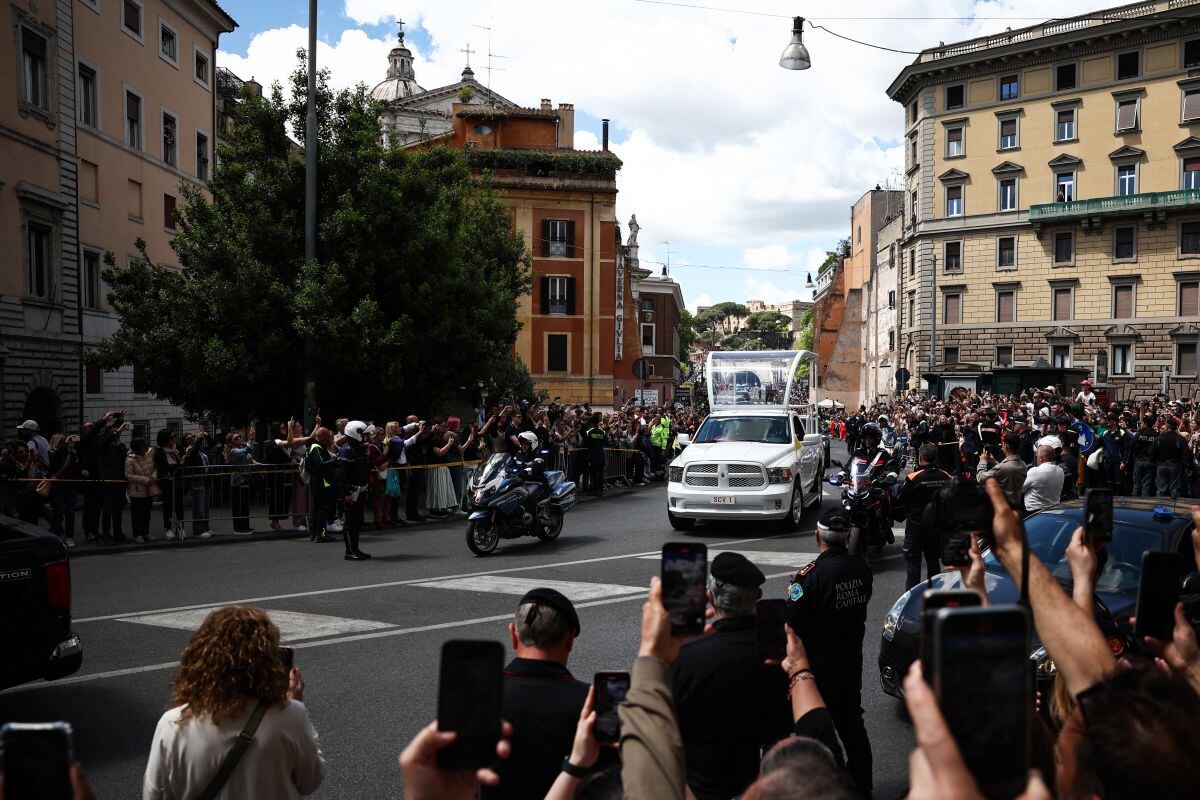 Fieles toman fotografías con sus teléfonos móviles del ataúd del difunto papa Francisco mientras es transportado en un papamóvil desde la Basílica de San Pedro a la Basílica de Santa María la Mayor, durante la ceremonia fúnebre en Roma el 26 de abril de 2025. (Foto de HENRY NICHOLLS / AFP)