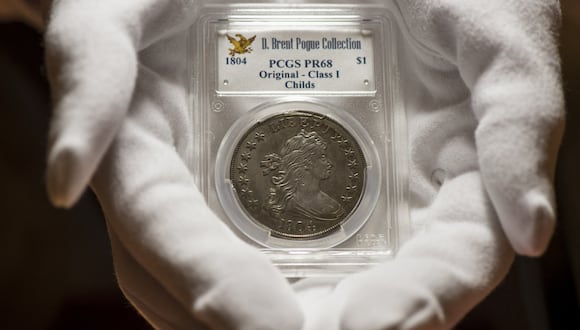 Un hombre sujetando un dólar de plata de 1804, una de las monedas más valiosas del mundo, que puede venderse en millones (Foto: AFP)
