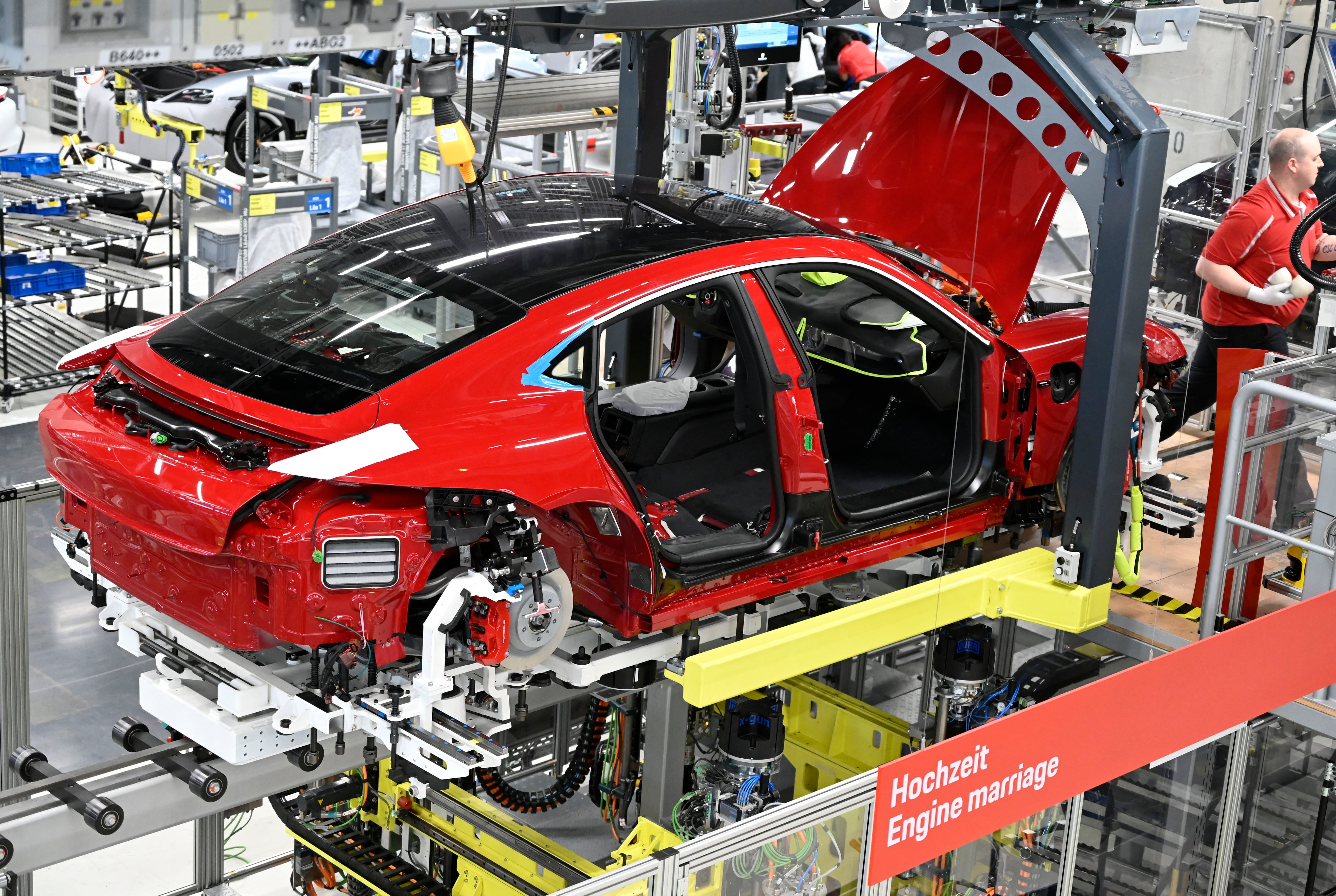 Un Porsche Taycan, el primer automóvil totalmente eléctrico del fabricante alemán de automóviles de lujo Porsche AG, se encuentra en la línea de montaje de la planta de la compañía en Stuttgart, al suroeste de Alemania, durante el proceso de ensamblaje, donde el chasis y el motor se unen a la carrocería. (Foto de THOMAS KIENZLE / AFP)