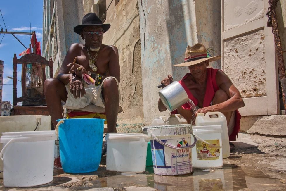 Oscar Joaquín López (izquierda) y su compañero de casa, Wilfredo Cisneros Duarte, recogen agua de una tubería en la calle en La Habana, Cuba, el 7 de septiembre de 2026. (AP Foto/Ramón Espinosa)