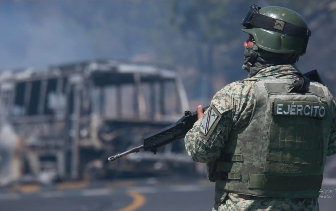 Un soldado vigila un vehículo calcinado tras ser incendiado en Cointzio, Michoacán, México, el domingo 22 de febrero de 2026, tras la muerte del líder del Cártel Jalisco Nueva Generación, Nemesio Oseguera, conocido como "El Mencho". (Foto AP/Armando Solis).