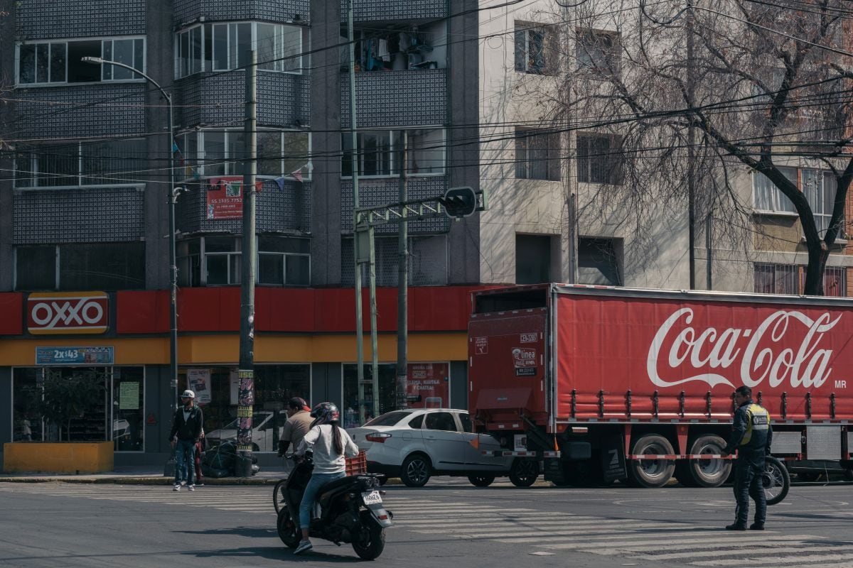 Un camión de reparto de Coca-Cola estacionado frente a una tienda de conveniencia OXXO en Ciudad de México.