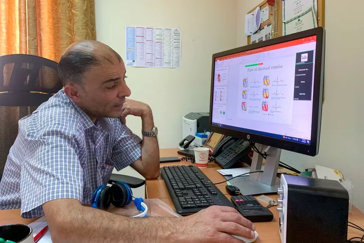 El profesor enseña en su teléfono un grupo de WhatsApp con cerca de 100 participantes en el que se comunica con los alumnos del curso de Enfermería Crítica. Si bien son 207 inscritos, en la sesión de ‘Zoom’ apenas hay tres conectados. (Foto: EFE)