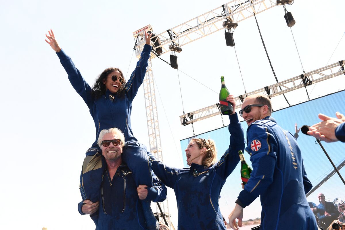 El fundador de Virgin Galactic, Sir Richard Branson (izquierda), con Sirisha Bandla sobre sus hombros, anima a los miembros de la tripulación después de volar al espacio a bordo de una nave de Virgin Galactic, un viaje que describió como la "experiencia de su vida", y que espera marque el comienzo de una era del turismo espacial en Spaceport America, cerca de Truth and Consequences, Nuevo México, el 11 de julio de 2021. (Foto de Patrick T. FALLON / AFP)