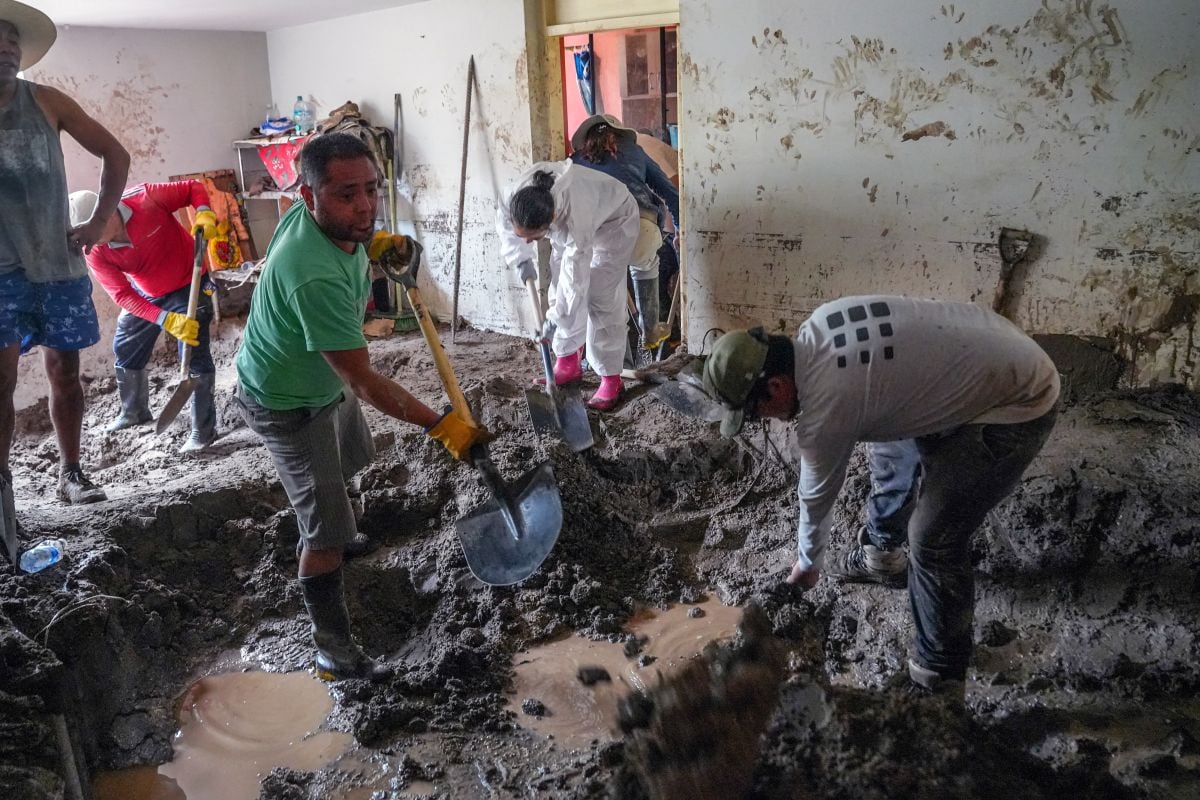Ciudadanos retiran el barro del interior de una casa tras las fuertes lluvias en la ciudad de Arequipa, el 25 de febrero de 2026 (Foto: Diego Ramos / AFP)