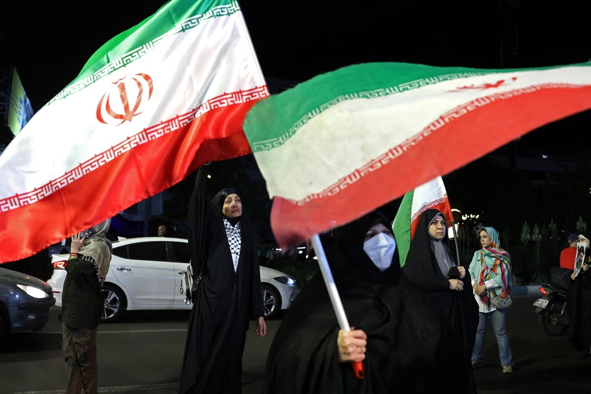 Mujeres portan banderas nacionales de Irán durante una protesta contra Estados Unidos e Israel en la plaza Hafte Tir de Teherán, el 17 de mayo de 2026. (AFP)