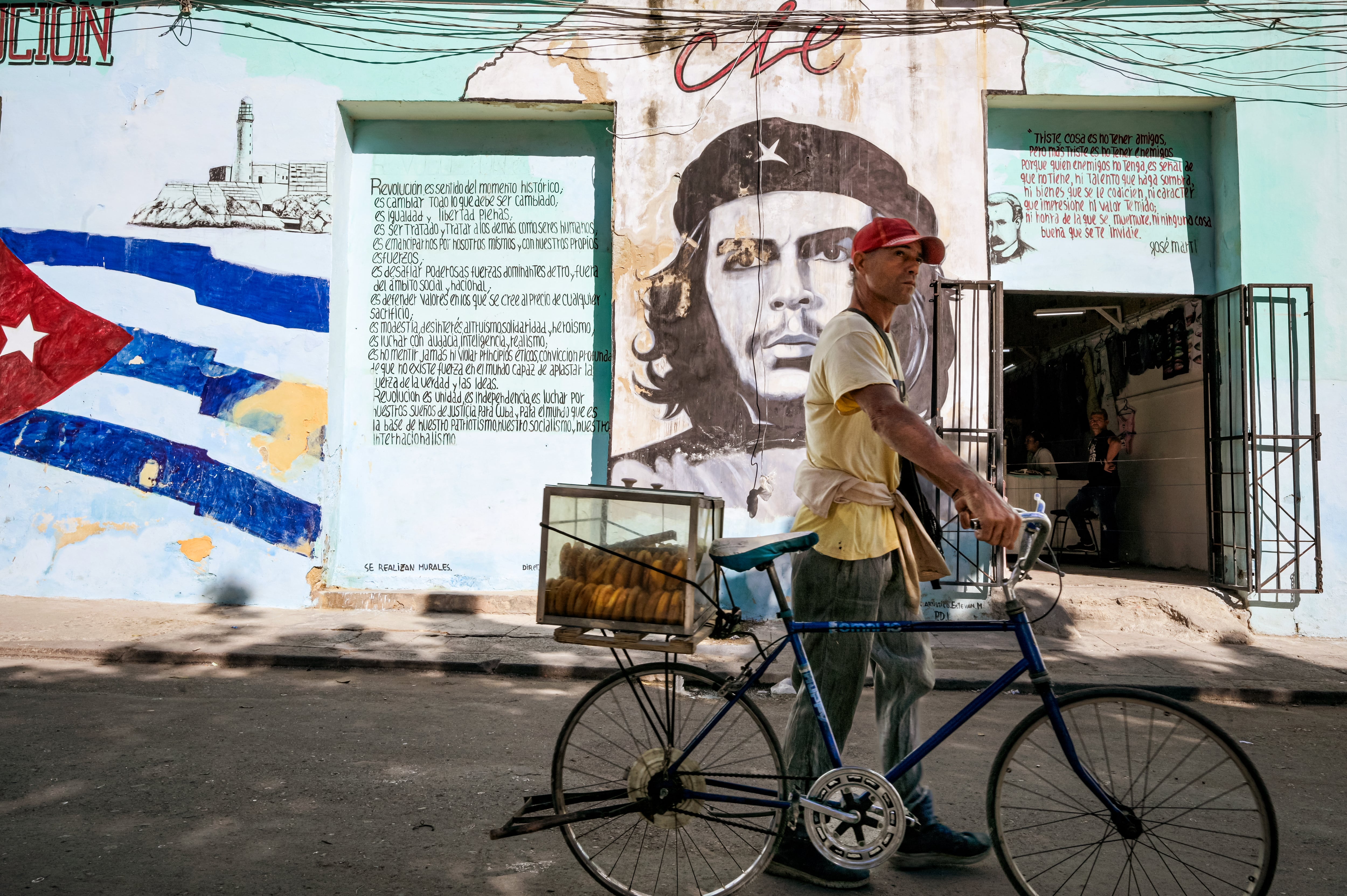 Un hombre vende pasteles frente a un mural del héroe de la Revolución cubana, Ernesto "Che" Guevara, en La Habana, el 6 de enero de 2026. (Foto de ADALBERTO ROQUE / AFP).