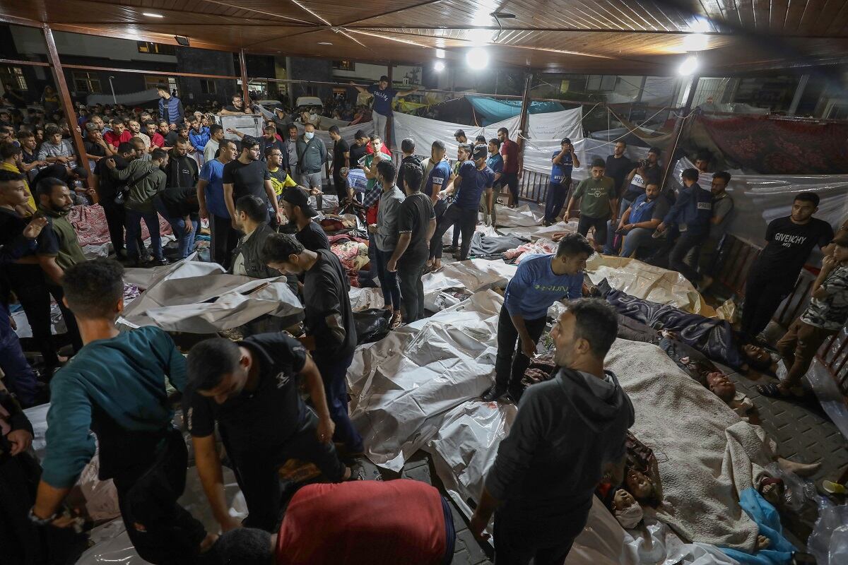 Gente se reúne alrededor de los cuerpos de los palestinos muertos después de que un ataque arrasara el hospital Ahli Arab en el centro de Gaza después de que fueron transportados al hospital Al-Shifa, el 17 de octubre de 2023. (Foto de Dawood NEMER / AFP)
