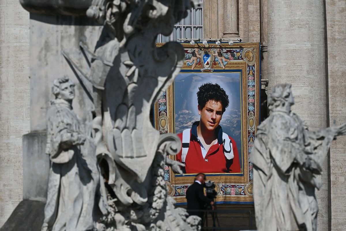 Un retrato del difunto adolescente italiano Carlo Acutis se exhibe en la fachada de la Basílica de San Pedro durante la Santa Misa y su canonización en la Plaza de San Pedro del Vaticano, el 7 de septiembre de 2025. (Foto de Filippo MONTEFORTE / AFP)