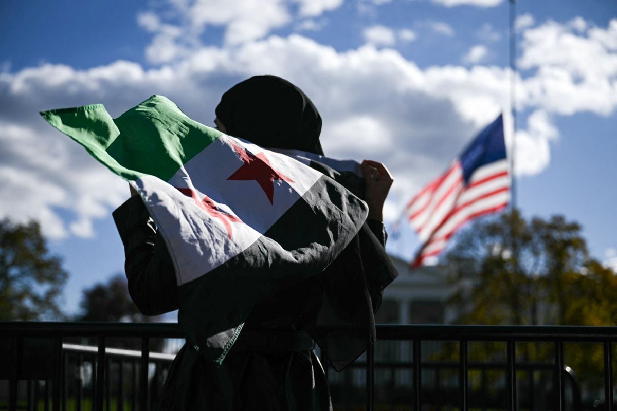 Un hombre sostiene una bandera siria frente a la Casa Blanca después de que el presidente sirio Ahmed al-Sharaa se reuniera con el presidente estadounidense Donald Trump en la Casa Blanca en Washington, DC, el 10 de noviembre de 2025. Foto: Brendan SMIALOWSKI / AFP