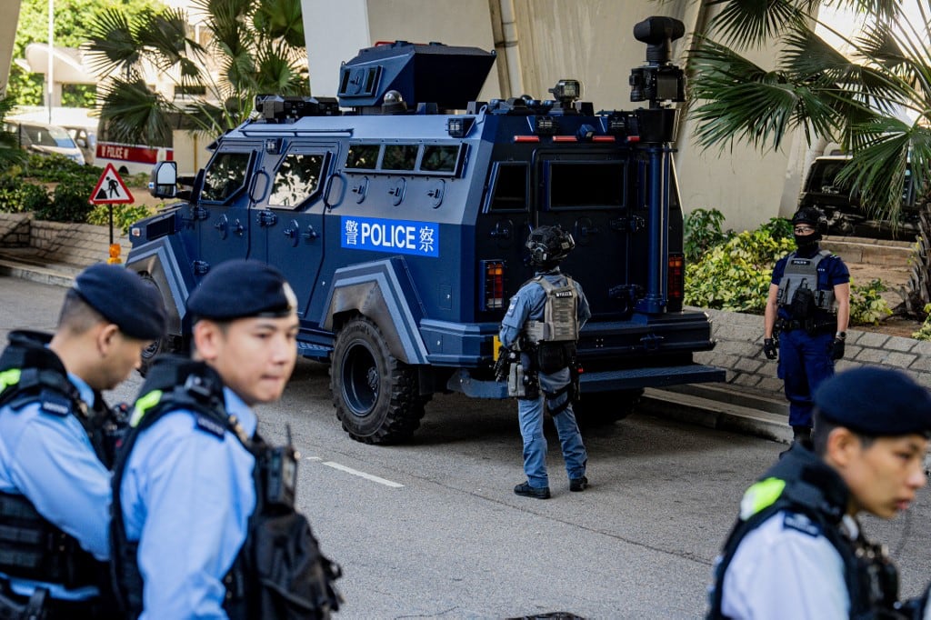 Policías armados vigilan junto a un vehículo blindado frente al tribunal de West Kowloon, donde se celebra el juicio por delitos de seguridad nacional contra el magnate de los medios Jimmy Lai en Hong Kong el 15 de diciembre de 2025. (Foto de Leung Man Hei / AFP)