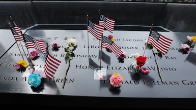 Flores, fotografías y otros recuerdos sobre los nombres en el sitio del memorial del 11 de septiembre, un día antes de las conmemoraciones de los ataques, en la ciudad de Nueva York, el 10 de septiembre de 2026. (SPENCER PLATT / Getty Images vía AFP)