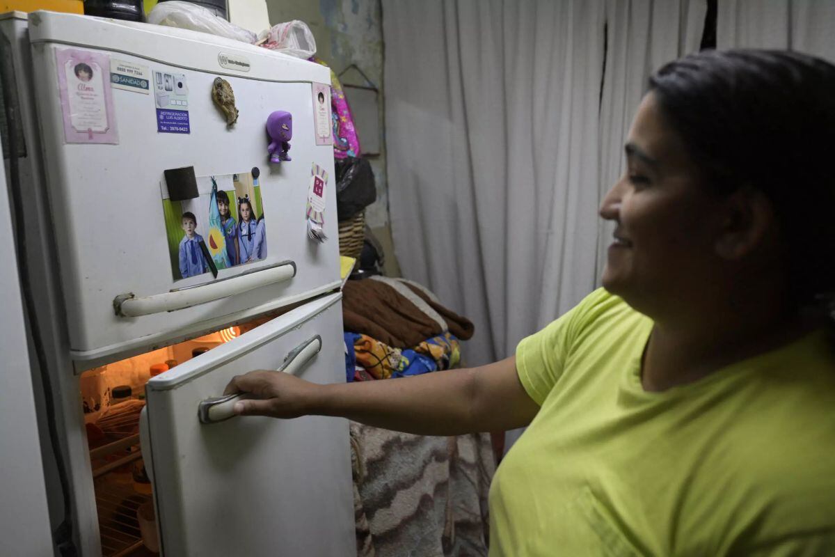Samanta Gómez, una enfermera que se recupera de un accidente cerebrovascular, abre el frigorífico en casa de su abuela, en Buenos Aires, donde vive con su pareja y sus tres hijos. |© Juan Mabromata / AFP