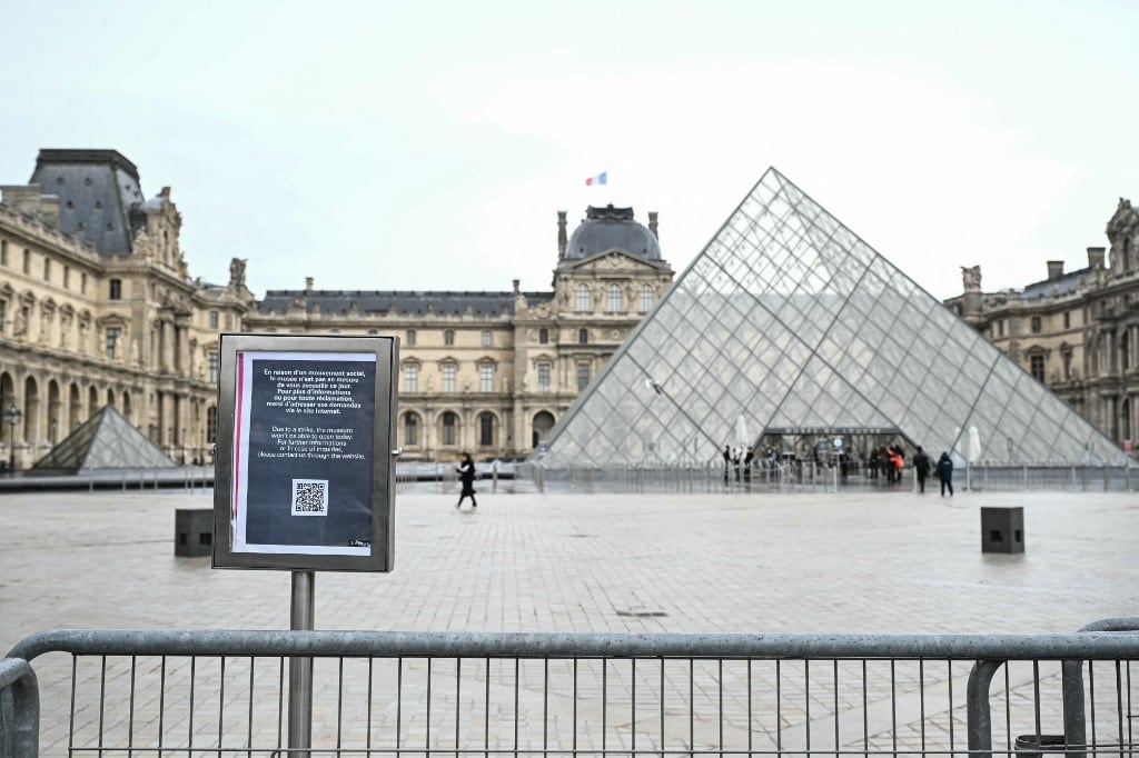 Una foto muestra un panel informativo que notifica el cierre del Museo del Louvre en la plaza vacía con la Pirámide del Louvre, diseñada por el arquitecto chino-estadounidense Ieoh Ming Pei, debido a una huelga en París el 12 de enero de 2026. El museo se vio obligado a cerrar el 12 de enero de 2026 después de que su personal, que ha estado en huelga desde mediados de diciembre en un intento por asegurar mejores condiciones laborales, decidiera continuar con su huelga, según supo AFP a través del museo y los sindicatos. (Foto de Martin LELIEVRE / AFP)