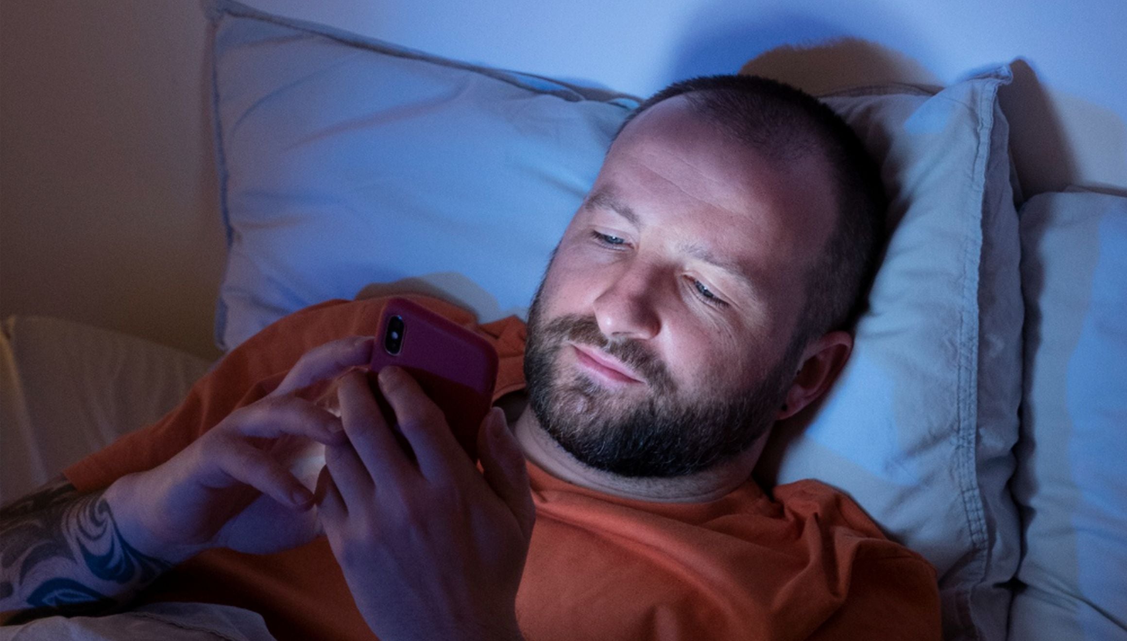 Esta imagen muestra a un hombre echado en su cama mientras mira su celular porque se le hace imposible dormir. (Foto: freepik)