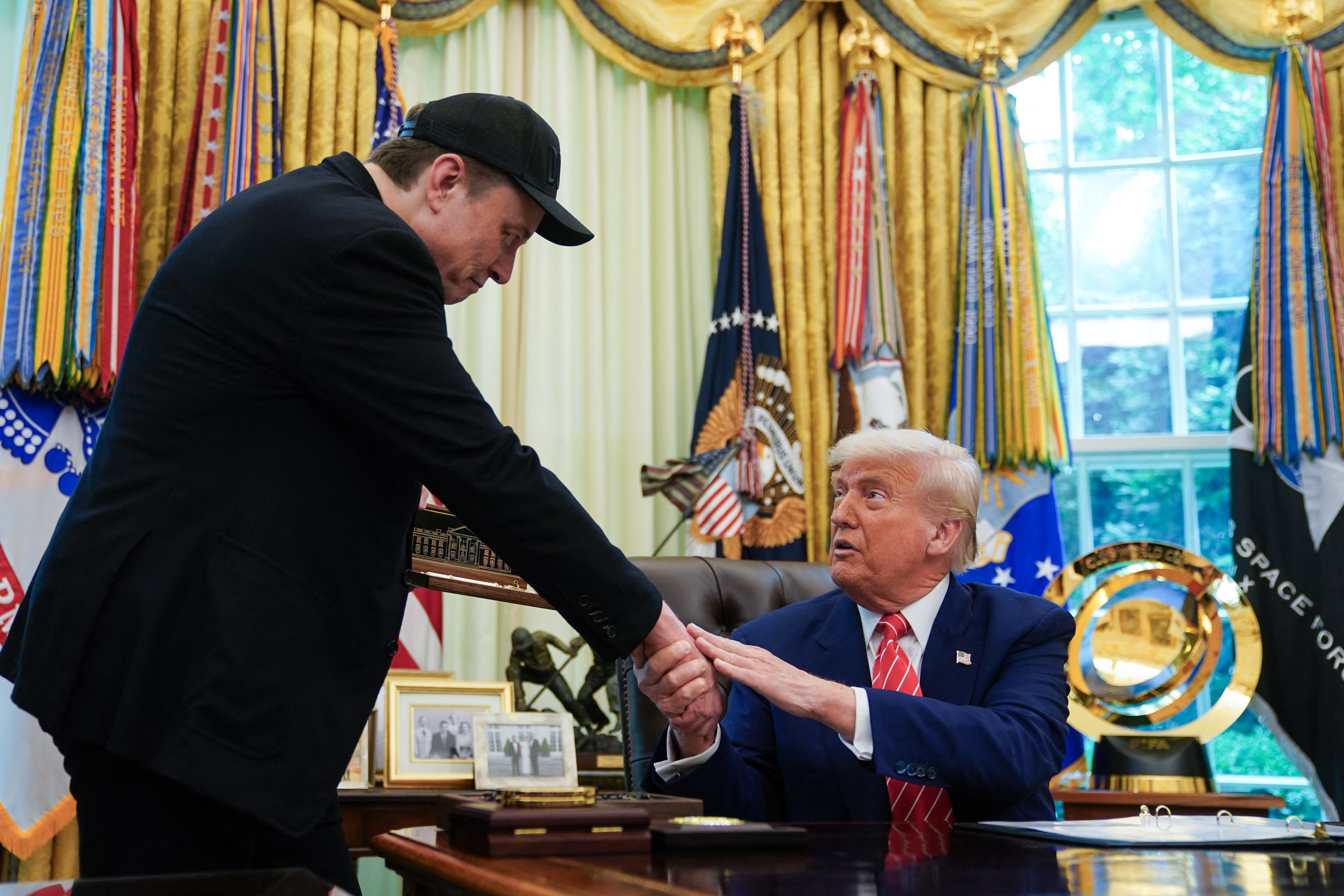 El presidente de Estados Unidos, Donald Trump, estrecha la mano de Elon Musk después de que Trump le entregara la "llave de la Casa Blanca" durante una conferencia de prensa en la Oficina Oval de la Casa Blanca en Washington, D.C., el 30 de mayo de 2025. (Foto de ALLISON ROBBERT / AFP)