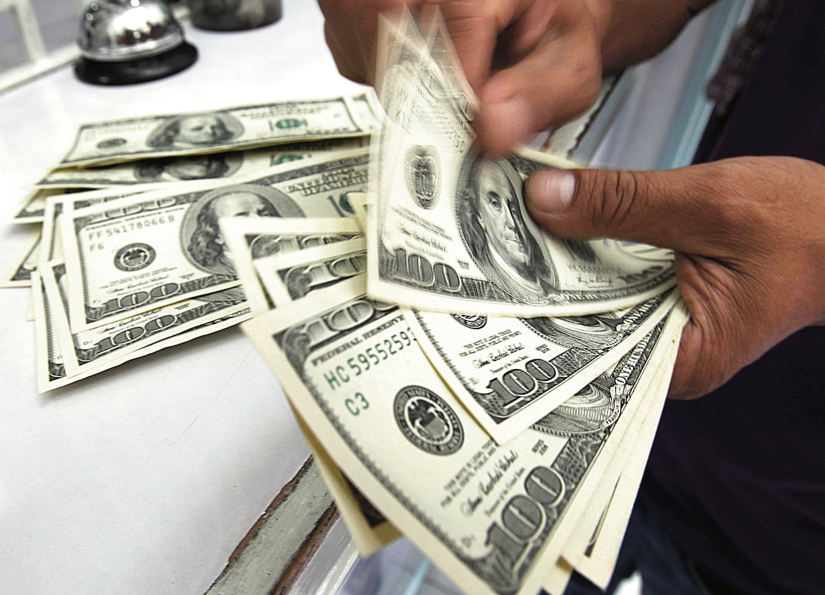 A worker counts U.S. dollar bills at a money changer in Manila August 10, 2011. The Philippines expects more money inflows after the Fed promised near zero rates up to 2013, potentially muddling monetary policy looking to bolster local demand, the central bank said on Wednesday. Policymakers would also continue a review of current rules to dampen volatilities in the foreign exchange market, Bangko Sentral ng Pilipinas (BSP) Governor Amando Tetangco said. REUTERS/Romeo Ranoco (PHILIPPINES - Tags: BUSINESS POLITICS) - RTR2PS6C