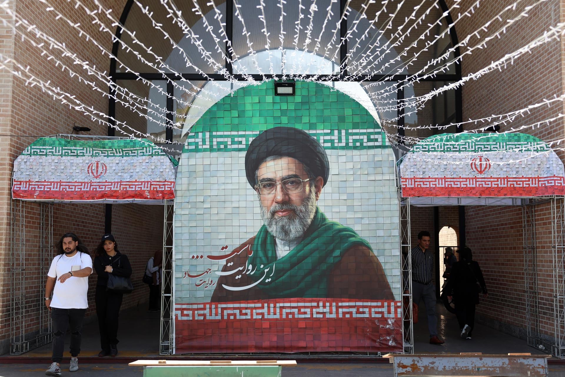 Ciudadanos de Irán caminan junto a una fotografía del líder supremo Mojtaba Jamenei en una calle de Teherán, el 6 de mayo de 2026. (EFE/EPA/ABEDIN TAHERKENAREH).