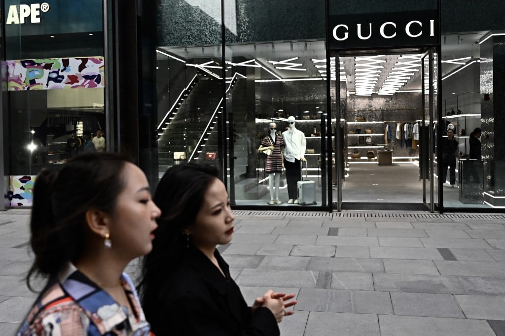 Peatones pasan frente a una tienda de Gucci en Pekín el 20 de abril de 2025. (Foto de Pedro PARDO / AFP)