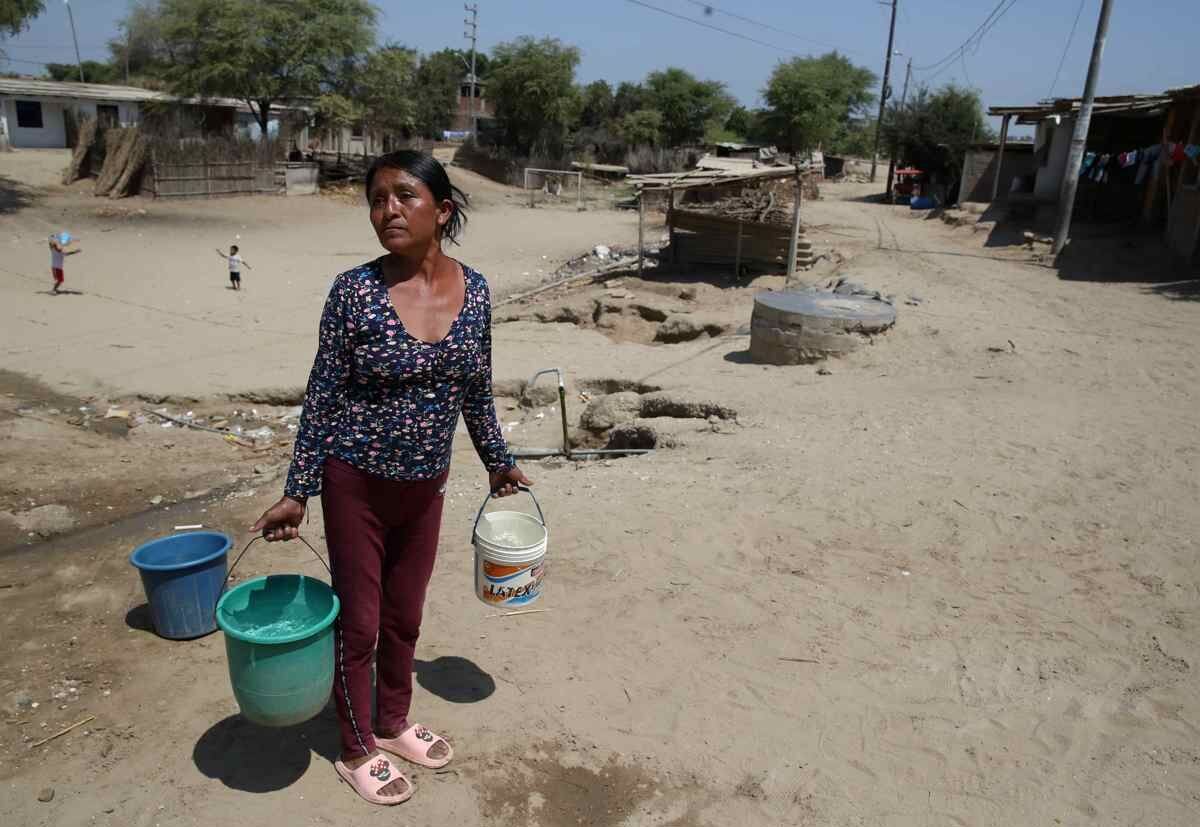 Una mujer carga baldes con agua de los bidones instalados por Acción contra el Hambre, el 6 de septiembre de 2023 en el asentamiento humano de Mocará, departamento de Piura (Perú). Foto: EFE