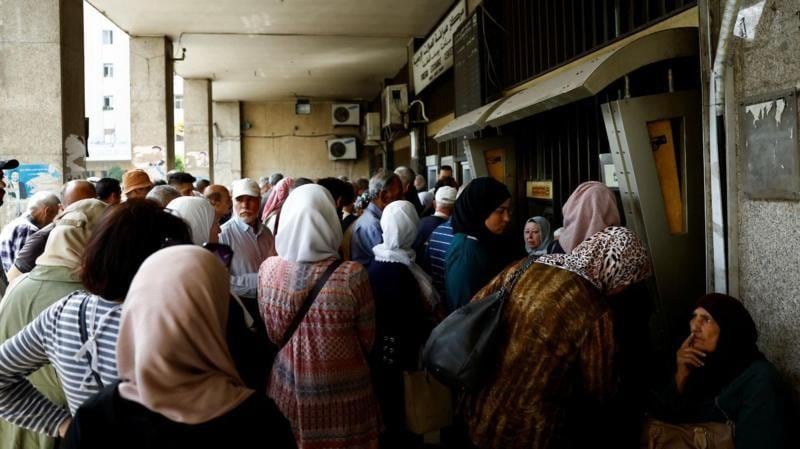 Personas se reúnen frente a un banco tras el anuncio de Trump del fin de las sanciones a Siria.
