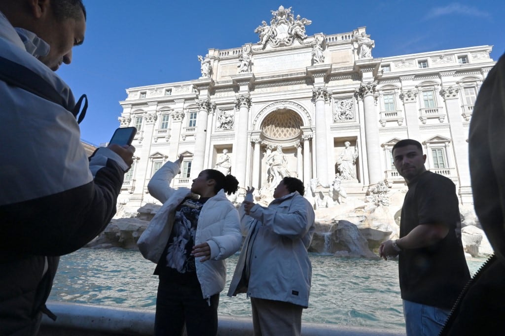 Los visitantes lanzan monedas a la Fontana di Trevi en Roma después de que la ciudad introdujera una entrada de pago de dos euros el 2 de febrero de 2026. (Foto de Andreas SOLARO / AFP)