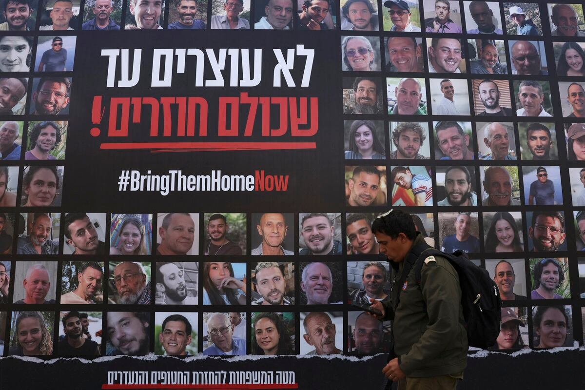 Un hombre pasa junto a un cartel que muestra retratos de rehenes israelíes retenidos en Gaza desde el ataque del 7 de octubre por militantes de Hamas, en Jerusalén, el 18 de noviembre de 2024. (Foto de HAZEM BADER / AFP)