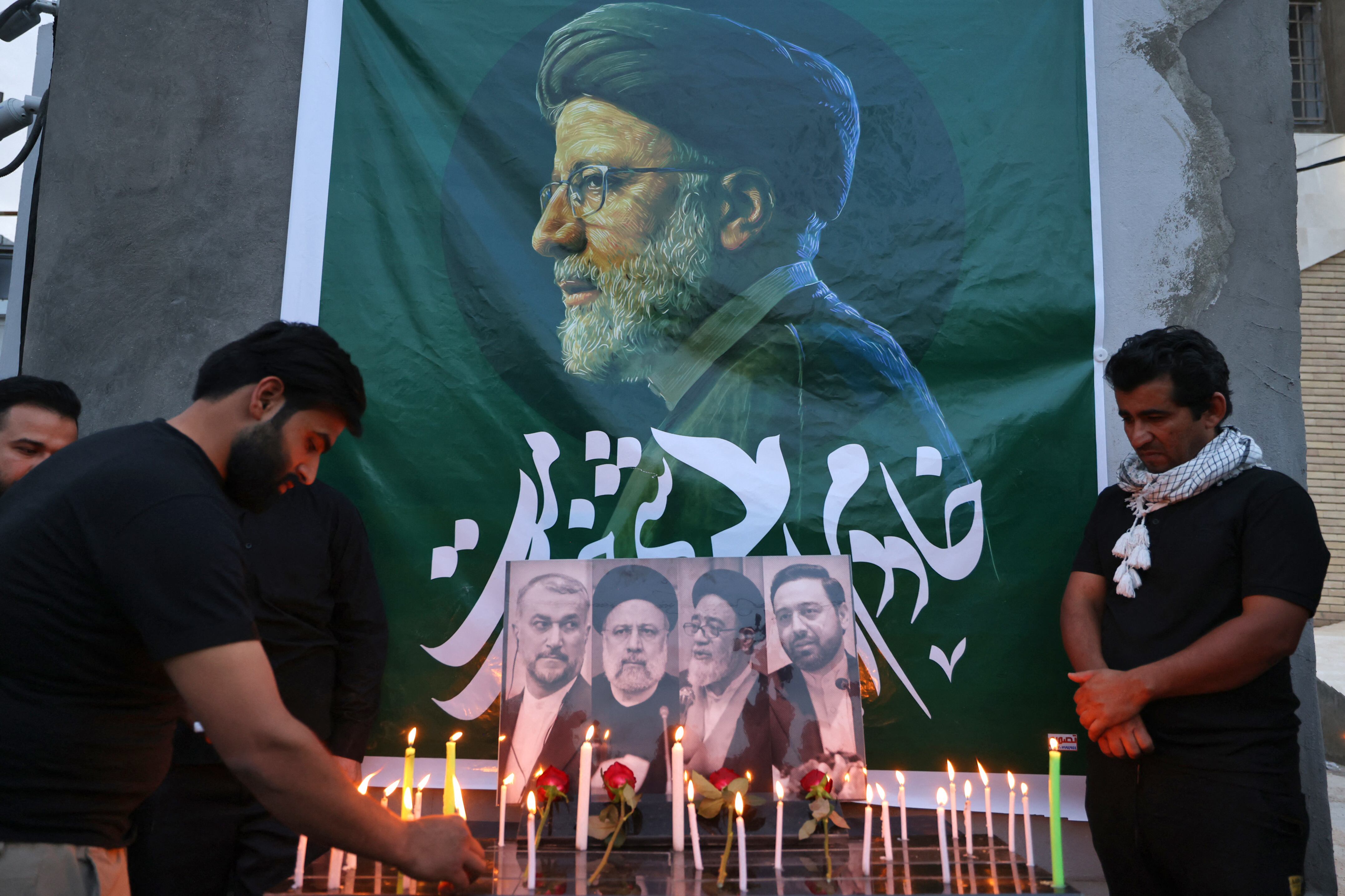 Los iraquíes encienden velas para el difunto presidente de Irán, Ebrahim Raisi (en la foto) frente a la embajada iraní en Bagdad durante un servicio de condolencias el 20 de mayo de 2024 para el presidente y su séquito, que murieron en un accidente de helicóptero en Irán el día anterior. El presidente iraní, Ebrahim Raisi, murió en un accidente de helicóptero el 19 de mayo cerca de la frontera entre Irán y Azerbaiyán tras su regreso de una visita oficial. Las víctimas fueron Raisi (en la pancarta y abajo, segundo a la izquierda), el ministro de Relaciones Exteriores Hossein Amir-Abdollahian (abajo a la izquierda), un gobernador provincial y un imán, junto con los tres tripulantes del avión y dos guardaespaldas, dijeron funcionarios iraníes. (Foto de AHMAD AL-RUBAYE / AFP)
