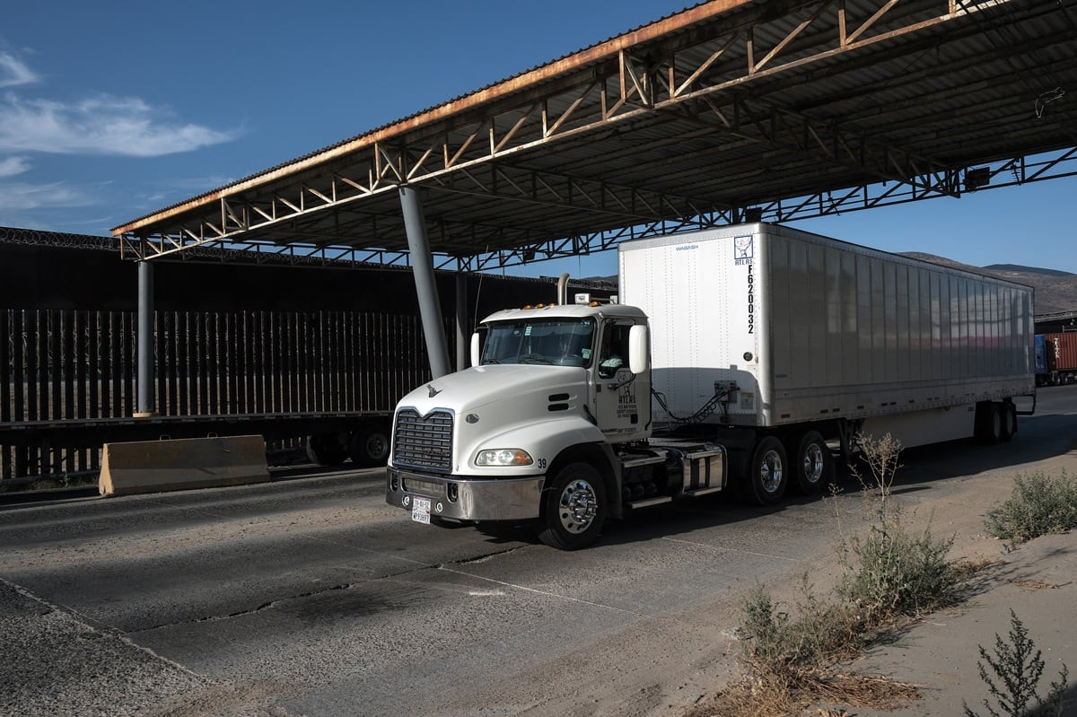Un camión de carga hace cola junto al muro fronterizo antes de cruzar a Estados Unidos en el puerto comercial de Otay en Tijuana, estado de Baja California, México, el 21 de agosto de 2025. (Foto de Guillermo Arias / AFP)