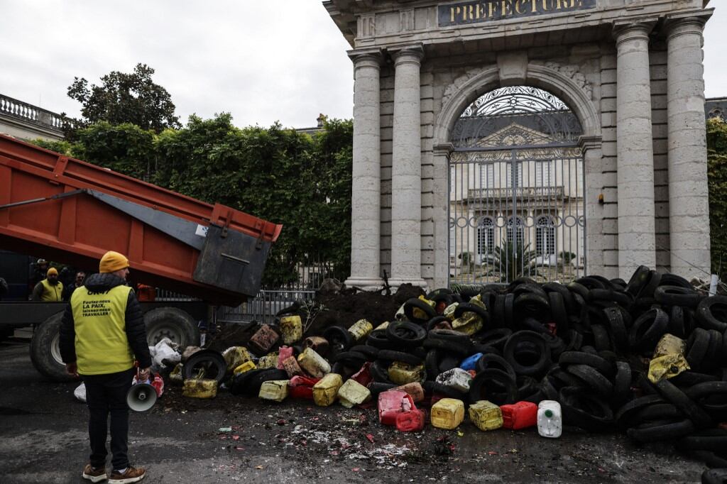 Los agricultores utilizan un camión para arrojar tierra, neumáticos usados y contenedores de plástico durante una protesta de agricultores frente a la prefectura de Agen el 19 de noviembre de 2024 como parte de un movimiento nacional contra el acuerdo UE-Mercosur. (Foto de Thibaud MORITZ / AFP)