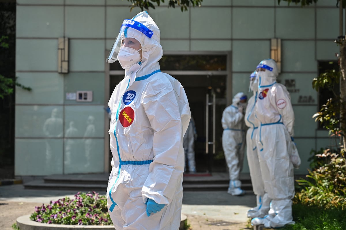 Trabajadores y voluntarios se paran en un recinto donde los residentes están siendo examinados para detectar el coronavirus Covid-19 durante la segunda etapa de un bloqueo pandémico en el distrito de Jing'an en Shanghái el 6 de abril de 2022. (Foto de HECTOR RETAMAL / AFP)