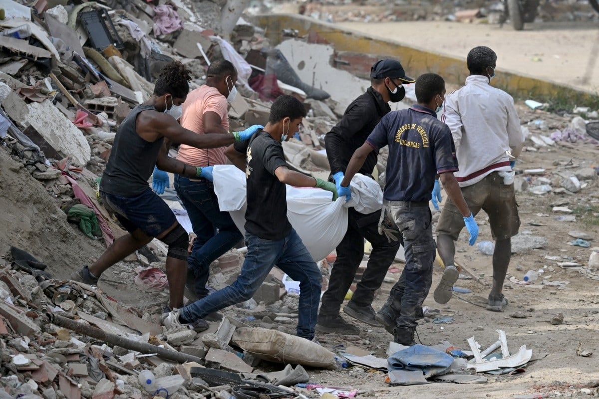 Rescatistas transportan el cuerpo de una víctima rescatada de entre los escombros de edificios derrumbados en Caraballeda, estado de La Guaira, Venezuela, el 8 de julio de 2026, tras los potentes terremotos que azotaron la región. (Raul ARBOLEDA / AFP)