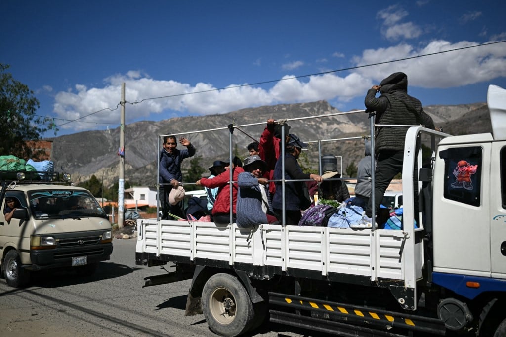 Varias personas viajan en la parte trasera de un camión tras la reapertura de una carretera después de las protestas que exigían la renuncia del presidente de Bolivia, Rodrigo Paz, en Carreras, departamento de La Paz, Bolivia, el 5 de junio de 2026. (Foto de Marvin RECINOS / AFP)