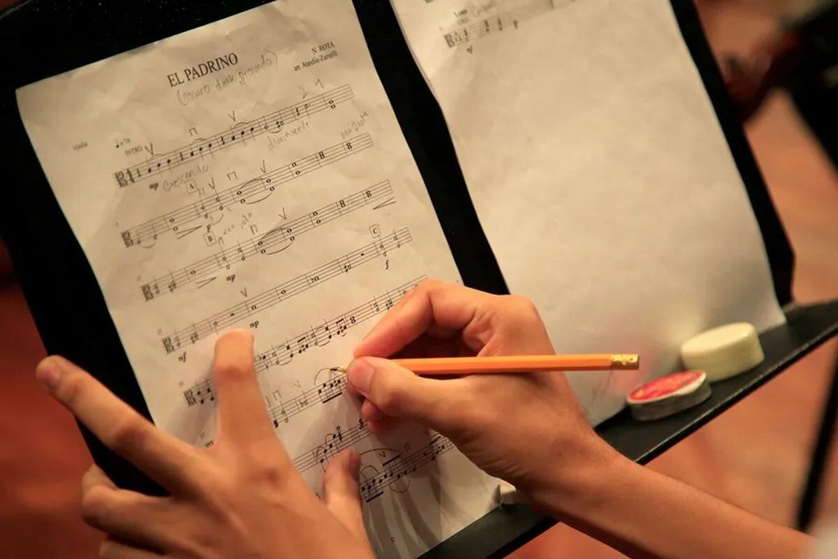 Un integrante de orquesta escribe sobre una partitura. EFE/Ricardo Maldonado/Archivo