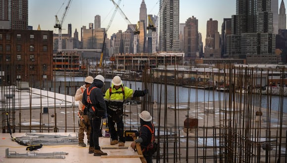 Una vista general muestra a los trabajadores de la construcción de pie ante el horizonte de Manhattan y el Empire State Building, en Brooklyn el 24 de enero de 2023. (Foto de Ed Jones / AFP)
