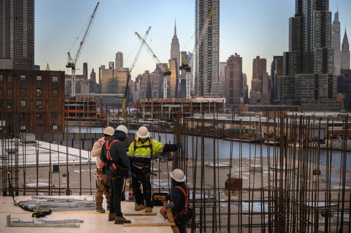 Una vista general muestra a los trabajadores de la construcción de pie ante el horizonte de Manhattan y el Empire State Building, en Brooklyn el 24 de enero de 2023. (Foto de Ed Jones / AFP)