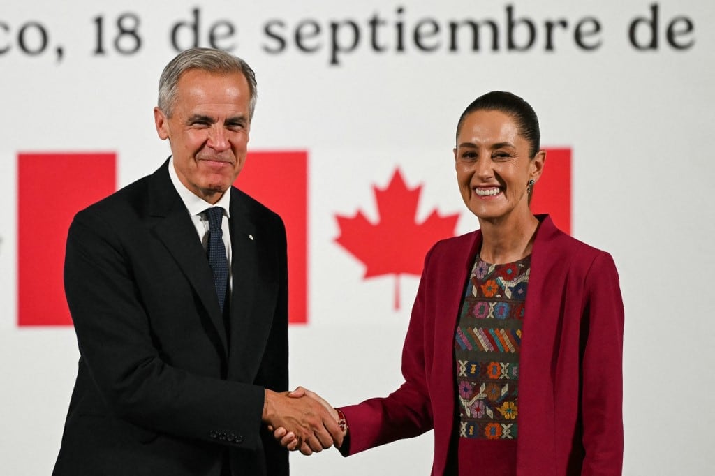 Canada's Prime Minister Mark Carney (L) and Mexico's President Claudia Sheinbaum (R) shake hands after a joint press conference at the National Palace in Mexico City on September 18, 2025. Mexico's President Claudia Sheinbaum and Canada's Prime Minister Mark Carney met in Mexico City as Trump pushes to renegotiate the USMCA North American trade pact in place since 2020. It replaced the NAFTA accord signed in the 1990s. (Photo by Yuri CORTEZ / AFP)